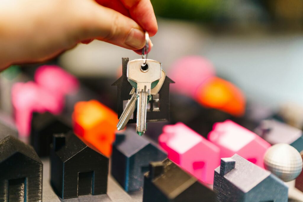 Hand holding new house keys above miniature model houses